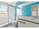 Bright bathroom with a shower, white vanity, and blue accent wall at 6125 Morningdale Ave, Lakeland, FL 33813
