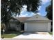 Charming single-story home featuring a two-car garage and a well-manicured front yard with mature tree at 6125 Morningdale Ave, Lakeland, FL 33813