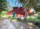 Exterior view of a home with a red exterior and green door, surrounded by lush greenery and mature trees at 2292 Se 170Th Avenue Rd, Silver Springs, FL 34488