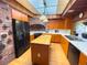 View of a bright kitchen with wooden cabinets, a black refrigerator, and an island cooktop at 2292 Se 170Th Avenue Rd, Silver Springs, FL 34488