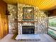 Stone fireplace with hearth, wooden mantel, and art displayed in bright, airy living room with paneled ceiling at 2292 Se 170Th Avenue Rd, Silver Springs, FL 34488