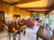 Comfortable living room with beamed ceilings, a stone fireplace, and bright natural light from the large windows at 2292 Se 170Th Avenue Rd, Silver Springs, FL 34488