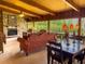 Spacious living room with a beamed ceiling, stone fireplace, and large windows showcasing the outdoors at 2292 Se 170Th Avenue Rd, Silver Springs, FL 34488