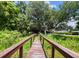 Scenic property entrance with a wooden bridge leading to a house under a large tree with Spanish moss at 2292 Se 170Th Avenue Rd, Silver Springs, FL 34488