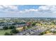 Expansive aerial view of a residential neighborhood, highlighting the community's layout amidst mature trees and a distant cityscape at 1890 Flora Pass Pl, Kissimmee, FL 34747