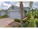 Charming home with a brick driveway, a two-car garage, and lush tropical landscaping at 1890 Flora Pass Pl, Kissimmee, FL 34747