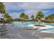 Beautiful community pool with tiled deck, mature palm trees, lounge chairs, and clear blue skies at 1890 Flora Pass Pl, Kissimmee, FL 34747