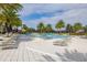 Community pool with lounge chairs, umbrellas, palm trees, a zero entry, and a lush green landscape at 1890 Flora Pass Pl, Kissimmee, FL 34747