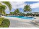 Community pool featuring clear blue water, palm trees, lounge chairs, lush landscaping, and blue skies at 1890 Flora Pass Pl, Kissimmee, FL 34747