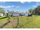 Spacious backyard with a black chain-link fence, patio with seating, and ample green space at 8225 Sw 108Th Street Rd, Ocala, FL 34481