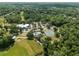 Aerial view of community clubhouse, pool, tennis courts and a long green golf course set among mature trees at 9700 Sw 196 Circle, Dunnellon, FL 34432