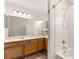 Well-lit bathroom features wooden cabinets, dual sinks and a shower-tub combo with white tile surround at 9700 Sw 196 Circle, Dunnellon, FL 34432