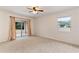 Spacious bedroom with plush carpeting, a ceiling fan, a window and sliding glass doors with peach curtains at 9700 Sw 196 Circle, Dunnellon, FL 34432