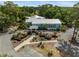 Aerial view of the clubhouse with blue siding and silver roof, surrounded by manicured landscaping at 9700 Sw 196 Circle, Dunnellon, FL 34432