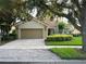 Charming home featuring a brick paver driveway leading to a two-car garage, set amidst lush landscaping at 12064 Navale Ln, Orlando, FL 32827