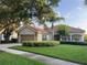 Charming single-story home with a red tile roof, a well-manicured lawn, and mature landscaping at 12064 Navale Ln, Orlando, FL 32827