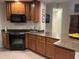 Kitchen featuring wood cabinets, black appliances, granite countertops, and tile flooring at 12064 Navale Ln, Orlando, FL 32827