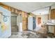 View of a kitchen with dated appliances, worn cabinets, and damaged flooring and walls at 303 Clayton Rd, Auburndale, FL 33823