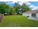 Expansive backyard with lush green grass, mature trees, a fire pit, and a patio with barbeque grill at 3826 Sleepy Hill Oaks Loop, Lakeland, FL 33810