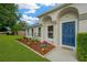 Charming home exterior featuring a blue door, manicured lawn, and landscaped garden bed at 3826 Sleepy Hill Oaks Loop, Lakeland, FL 33810