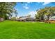 Expansive backyard featuring lush green grass, mature trees, a screened-in porch, and a fenced perimeter at 722 Swaying Palm Dr, Apopka, FL 32712