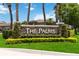 Stone entrance sign for 'The Palms' community, adorned with manicured greenery and a well-maintained lawn at 722 Swaying Palm Dr, Apopka, FL 32712