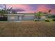 Charming single-story home featuring a gray brick exterior and manicured landscaping against a vivid sunset backdrop at 837 E Edgewood Dr, Lakeland, FL 33803