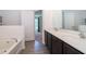 Bright bathroom features a soaking tub, double vanity, and a view into the bedroom at 27 Perch Dr, Kissimmee, FL 34759