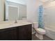 Well-lit bathroom showcases a single vanity, toilet, and a shower with a patterned curtain at 27 Perch Dr, Kissimmee, FL 34759