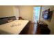Clean bedroom with a bed, hardwood floors, a window for natural light, and a view to the bathroom at 7810 Whitemarsh Way, Reunion, FL 34747