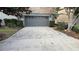 A gray, two car garage featuring a stone-paved driveway and manicured landscaping at 7810 Whitemarsh Way, Reunion, FL 34747