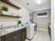 Bright laundry room with washer, dryer, granite countertop, shelving, and sink at 9080 Morgana Ct, Winter Garden, FL 34787