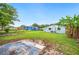 Large backyard with a concrete patio, lush grass, banana trees, and a charming blue house at 1022 Baycrest Dr, Lakeland, FL 33805