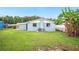 Green backyard showcasing a blue house with an AC unit and banana trees near a white fence at 1022 Baycrest Dr, Lakeland, FL 33805