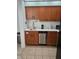 Efficient kitchenette with wood cabinets, stainless dishwasher, and essential appliances, perfect for simple meal prep at 7601 Canada Ave # 220, Orlando, FL 32819