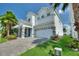 Inviting two-story home featuring a paver driveway, well-kept lawn, and lush tropical landscaping at 1423 Bunker Dr, Davenport, FL 33896