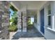 Covered front porch with stone pillars, tiled floor and a blue front door at 1423 Bunker Dr, Davenport, FL 33896