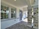 Covered front porch featuring stone pillars, tiled floor and a blue front door at 1423 Bunker Dr, Davenport, FL 33896