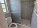 Bathroom featuring tiled walls, shower and flooring with a toilet and window at 3115 Lake Arnold Pl, Orlando, FL 32806