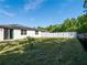 Large backyard with a white fence, black chain-link fence, and solar panels on the house at 573 Vista Villages Blvd, Davenport, FL 33896