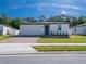 Charming single-story home features a well-manicured lawn, brick driveway, and a neutral-colored facade under a sunny sky at 573 Vista Villages Blvd, Davenport, FL 33896
