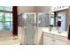 Bright bathroom showcasing a glass-enclosed shower, soaking tub, and vanity with modern fixtures and a large window at 433 Woodcrest St, Winter Springs, FL 32708
