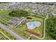 Aerial view of a community pool area with lounge chairs, palm trees, parking, and a playground at 5660 Keaton Springs Dr, Lakeland, FL 33811