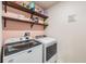 Laundry room with white washer and dryer, open shelving and pink walls at 5660 Keaton Springs Dr, Lakeland, FL 33811