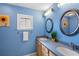 Bathroom with blue walls, dual vanity, framed mirrors, and a window providing natural light at 6143 Black Walnut Dr, Bartow, FL 33830