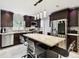 Modern kitchen featuring dark cabinets, stainless steel appliances, and a kitchen island with seating and decorative hanging lights at 229 Temple Ave, Fern Park, FL 32730