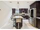 Modern kitchen featuring dark cabinets, stainless steel appliances, and a kitchen island with barstool seating and tile floors at 229 Temple Ave, Fern Park, FL 32730