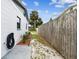 Narrow side yard with wood fence, plants, and a hose reel mounted to the house at 229 Temple Ave, Fern Park, FL 32730