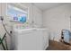 Bright laundry area with white appliances, a window for natural light, and painted brick walls at 4003 Prairie Bend Ln, Lakeland, FL 33812