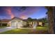 Lovely single-story home with lush landscaping, showcasing curb appeal under a stunning evening sky at 647 San Pedro Dr, Lady Lake, FL 32159